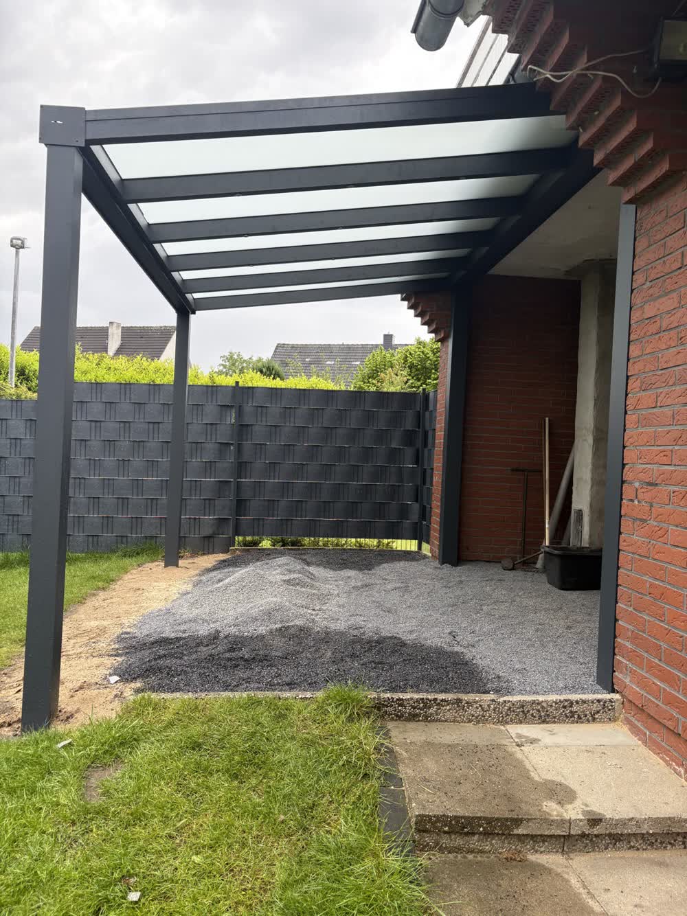 Aluminium-Terrassenüberdachung mit Glasdach über einer Terrasse mit Sitzgruppe